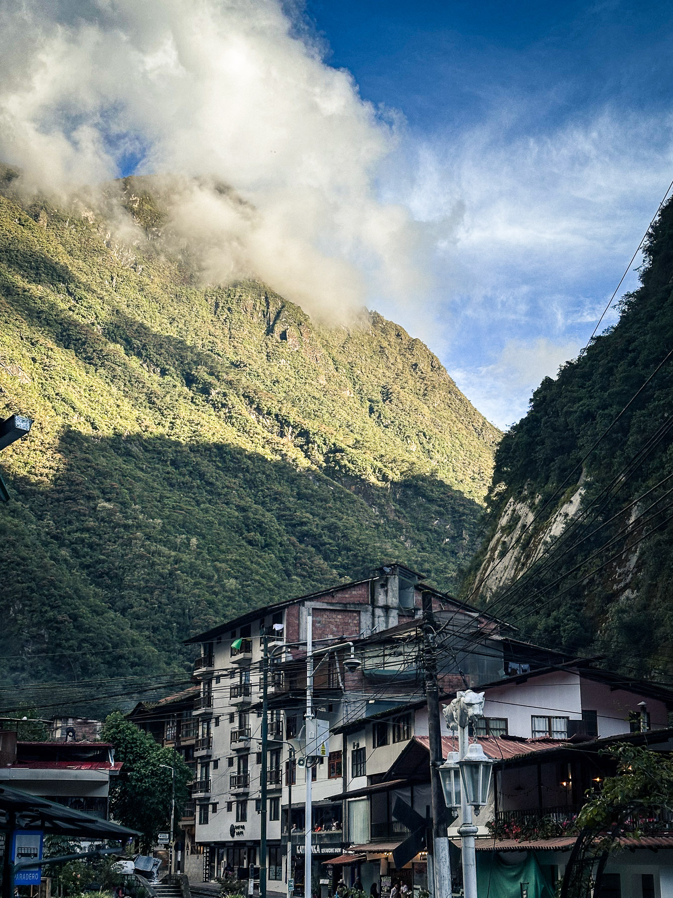 Street scene in Aguas Calientes, Peru, with steep green mountains rising behind the town.