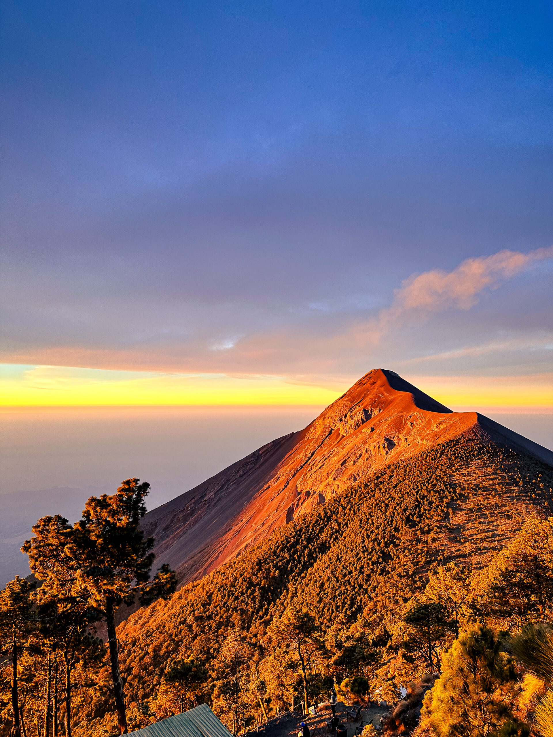 Volcán de Fuego at sunrise with golden light on the slopes, seen from Wicho & Charlie Acatenango base camp in Guatemala